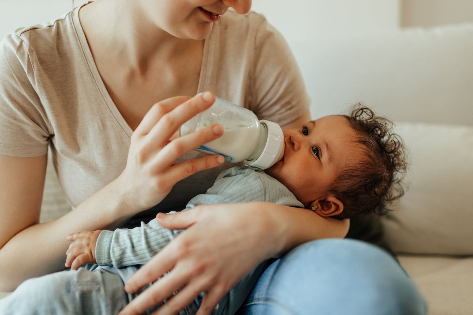 Bebé tomando la mamadera en brazos de su mamá